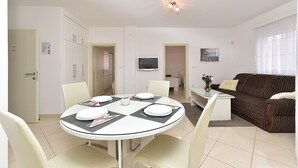 Een eetruimte met een ronde tafel voor vier personen, een bank en een televisie aan de muur.