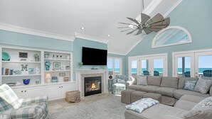A spacious living room with a fireplace, comfortable seating, a television, and a view of the ocean. - 7-Bedroom Home w/ Private Pool & Beach Access (Garden City Beach)