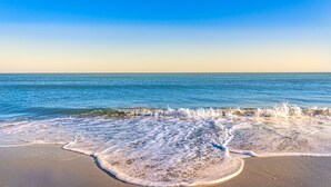 A beach with waves crashing onto the shore under a clear sky. - 7-Bedroom Home w/ Private Pool & Beach Access (Garden City Beach)