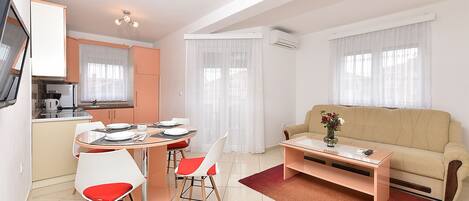 A compact living space with a dining area, kitchenette, and a sofa.