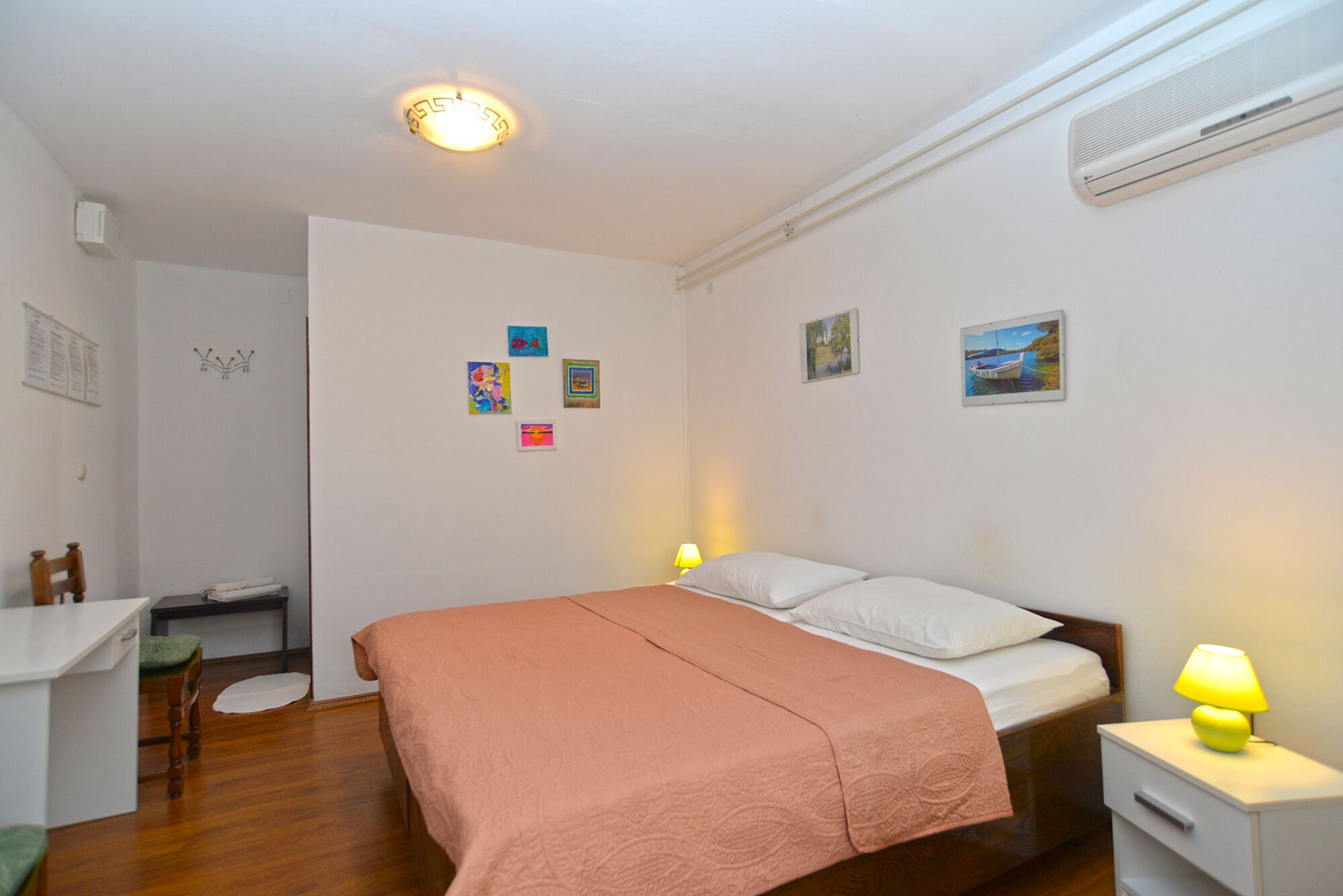 A bedroom with a bed, bedside table, lamp, and a desk with chair.