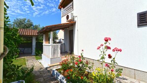 A white building with a covered patio, a small garden with flowers, and a clear blue sky. - Apartment 405/917 (Istria - Medulin), 300m from the beach (Medulin)