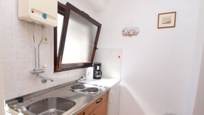 A compact kitchen with a stainless steel sink, a coffee maker, and a mirror above the counter.