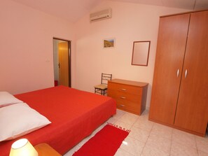 Une chambre à coucher avec un lit, une armoire en bois, une chaise, une petite table et une lampe.