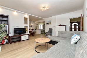 Una sala de estar con televisor, sofá y comedor.