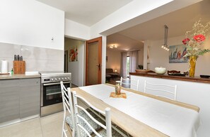Una cocina moderna con comedor, que incluye una isla grande, horno empotrado y una mesa de comedor con sillas.