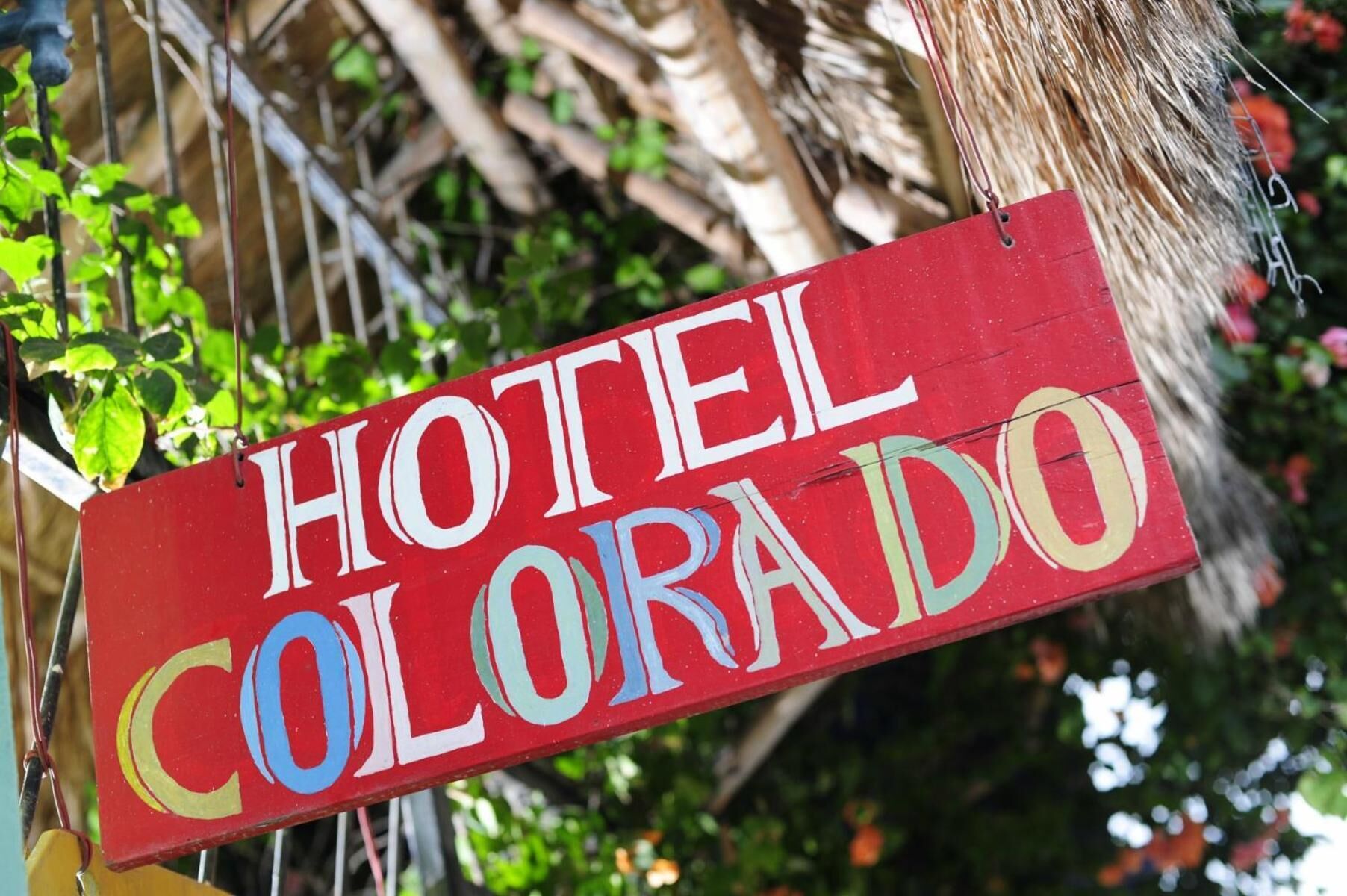 A wooden sign with the words "HOTEL COLORADO" painted in white, blue, and yellow.