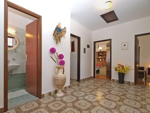 Stunning hallway with a geometric patterned floor, leading to various rooms, featuring a decorative vase and a small ornate vase with a floral arrangement.