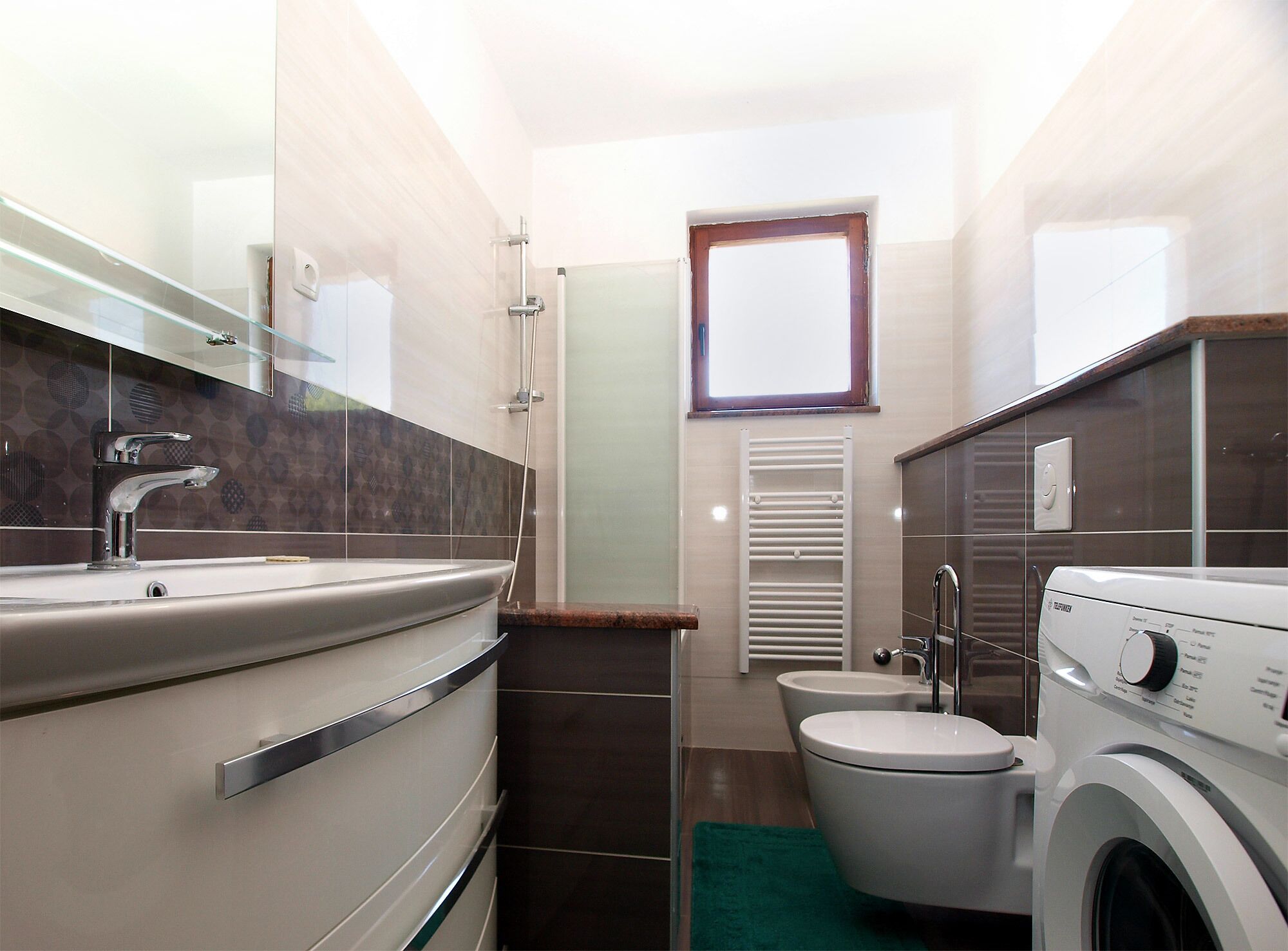 Ein kleines Badezimmer mit Waschbecken, Toilette und Waschmaschine.