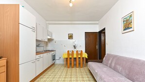 Une cuisine de taille réduite comprenant une table à manger, un canapé et une porte donnant sur une autre pièce.