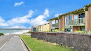 Una zona residenziale sul lungomare, con una strada asfaltata, un muro di pietra e case con balconi affacciati sul mare.