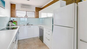 Una cucina moderna con mobili bianchi, una lavastoviglie in acciaio inossidabile e un frigorifero spazioso.