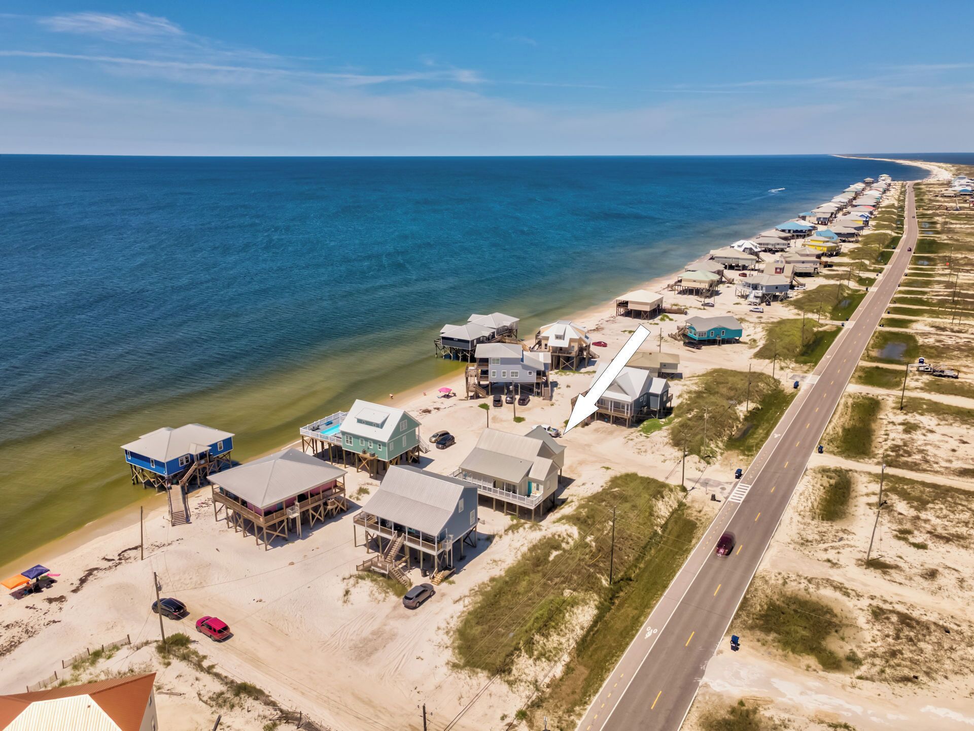 An aerial view of a coastal area with beachfront properties, a road, and a beach.