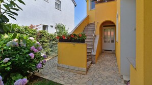 A yellow building with a stone staircase leading to a door, surrounded by greenery and flowers. - Apartment 436/1001 (Istria - Valbandon), 750m from the beach (Valbandon)