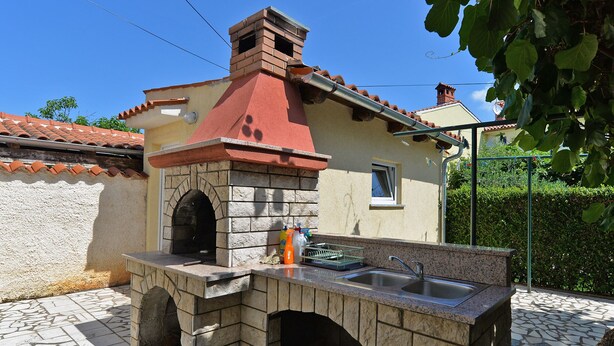 An outdoor kitchen with a stone oven, a sink, and a window. - Apartment 436/1001 (Istria - Valbandon), 750m from the beach (Valbandon)