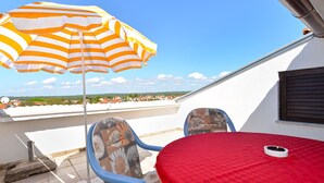 A terrace with a striped umbrella, two blue chairs, and a red table. - Apartment 442/1014 (Istria - Valbandon), 850m from the beach (Valbandon)