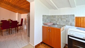 A compact kitchen with wooden cabinets, a tiled backsplash, and a white stove. - Apartment 442/1014 (Istria - Valbandon), 850m from the beach (Valbandon)