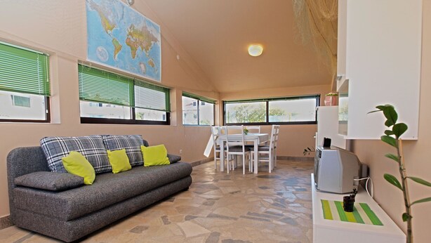 A living room with a grey sofa, a dining table with chairs, a map on the wall, and a small TV on a stand. - Apartment 531/1273 (Istria - Stinjan), 700m from the beach (Stinjan)