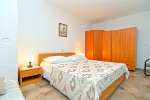 Un dormitorio con cama, mesita de noche, armario y un cuadro colgado en la pared.