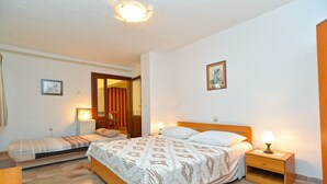 A bedroom with a large bed, a smaller bed, a nightstand, a chair, and a door leading to another room. - Apartment 534/1277 (Istria - Stinjan), 500m from the beach (Stinjan)