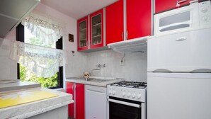 A kitchen with red cabinets, a white stove, a white dishwasher, and a microwave. - House 561/1347 (Istria - Rakalj), 2500m from the beach (Rakalj)