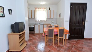 A compact kitchen with a dining area, a television, and a dark wooden door. - Apartment 590/1429 (Istria - Valbandon), 1000m from the beach (Valbandon)