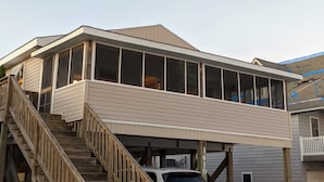 A two-story building with a covered porch and a wooden staircase.