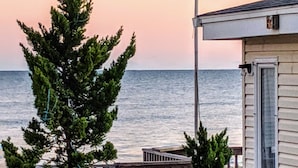 A wooden deck leading to a house with a view of the ocean.