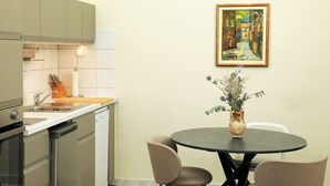 A modern kitchen with a dining area, featuring a round table, chairs, and a vase with flowers.