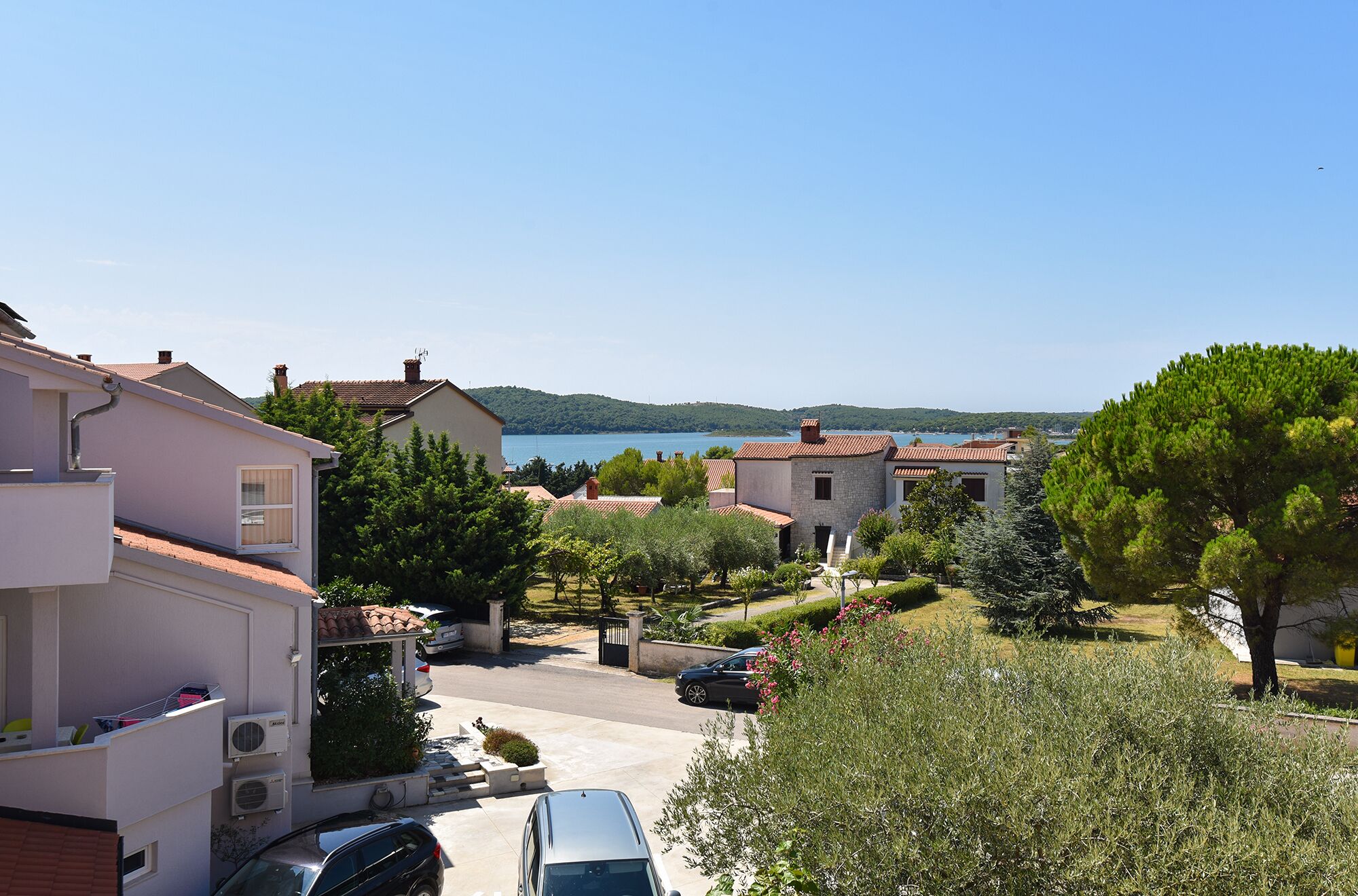 A residential area with houses, a clear blue sky, and a body of water in the background.