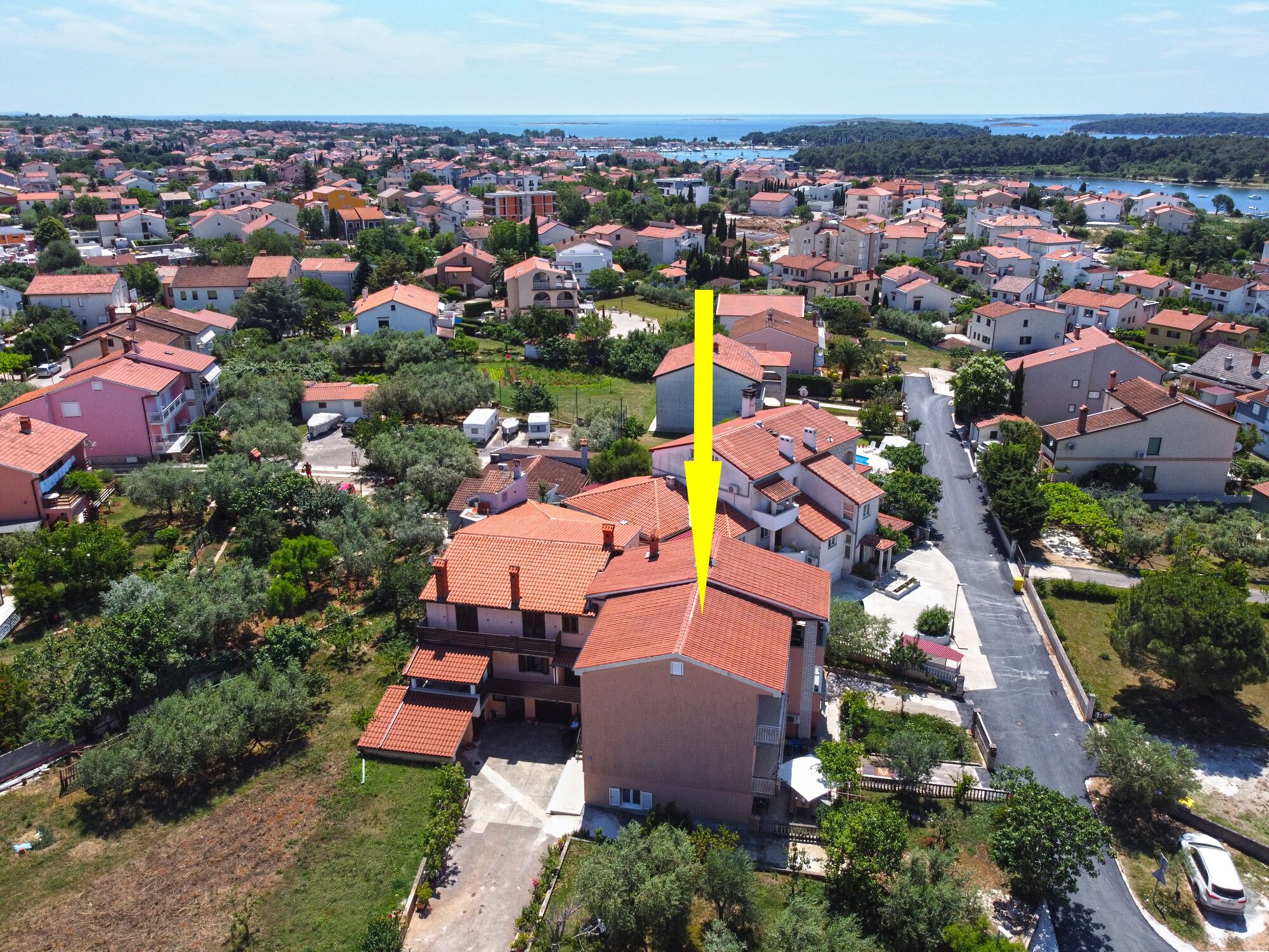 Vista aerea di una zona residenziale con case, strade e un corso d'acqua sullo sfondo.
