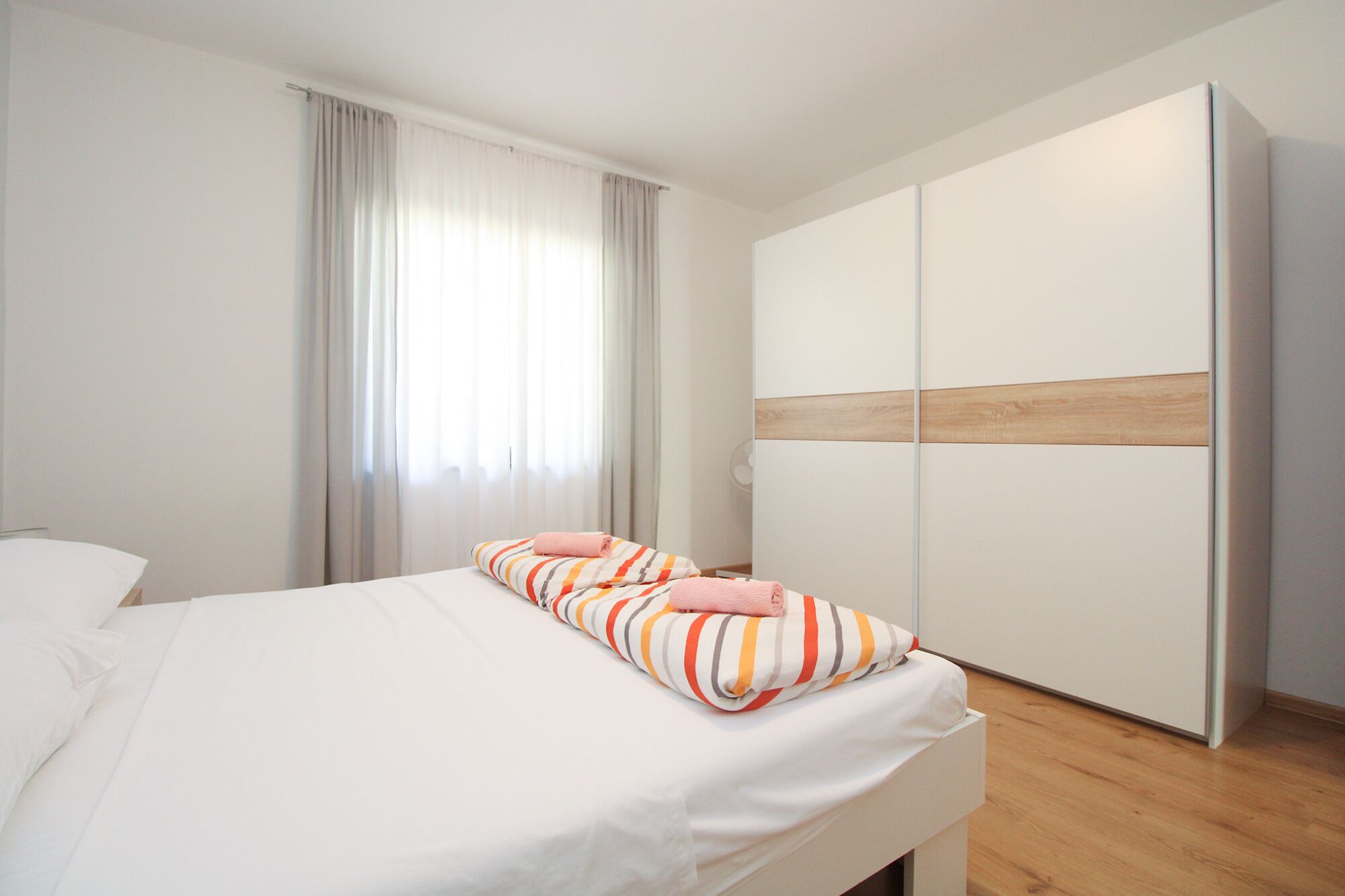 A hotel room with a bed, a wardrobe, and a window with curtains.
