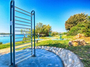A metal gate leading to a park with exercise equipment and a stone pathway.