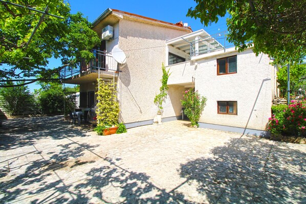 A two-story building with a balcony, a satellite dish, and potted plants.