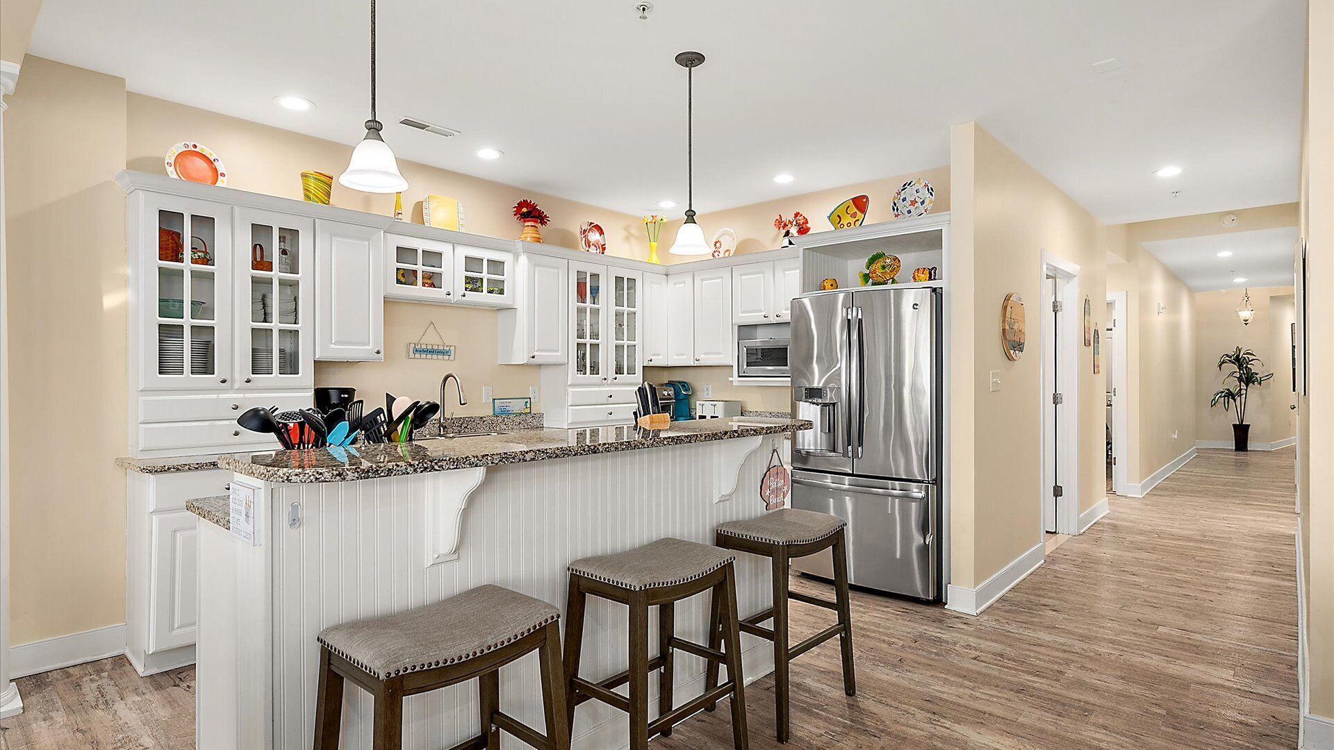 A modern kitchen with white cabinetry, stainless steel appliances, and a bar area with stools.