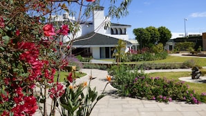 Un edificio bianco con tetto in tegole, immerso in un giardino curato con diverse piante e fiori.