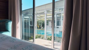 Una camera da letto con un'ampia finestra vista piscina e area vetrata.