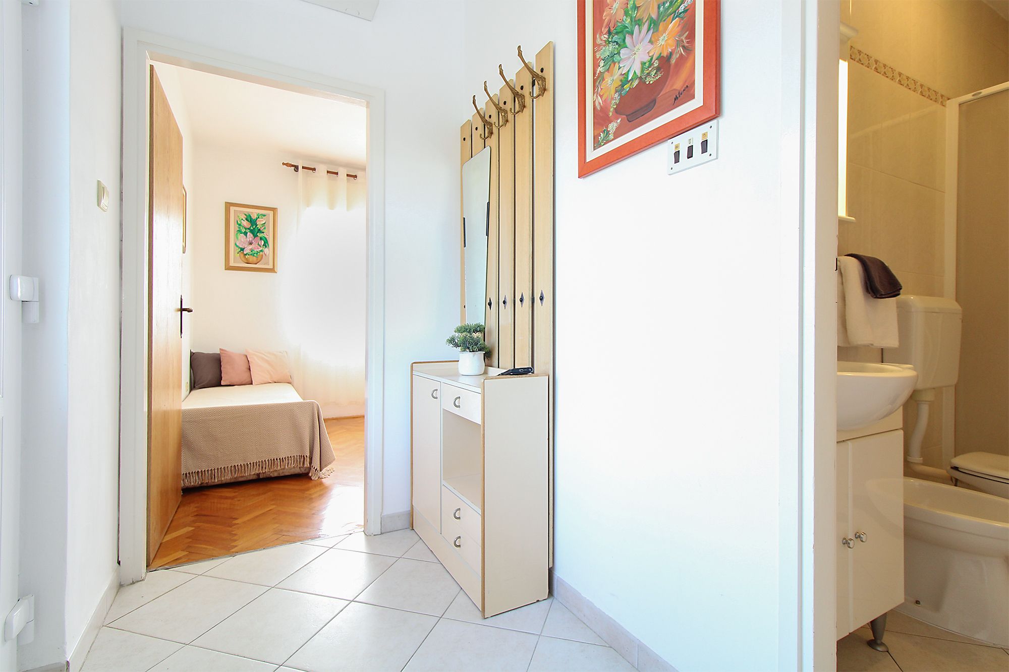 A hotel room with a bed, a wardrobe, a bathroom, and a painting on the wall.