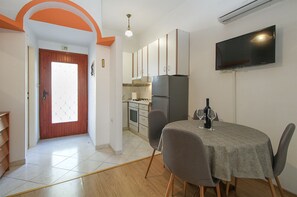 A compact kitchen with a refrigerator, stove, and dining area with chairs and a table. - Apartment 613/1470 (Istria - Pula), 500m from the beach (Pula)