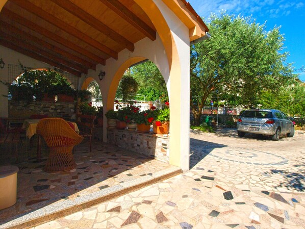 A covered outdoor seating area with mosaic flooring, a wicker chair, and potted plants. - Apartment 613/1470 (Istria - Pula), 500m from the beach (Pula)