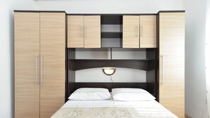 A bedroom with a bed, two cabinets, and a shelf unit.