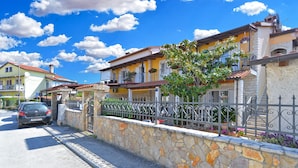 A residential street with stone walls, a metal fence, and houses with balconies.