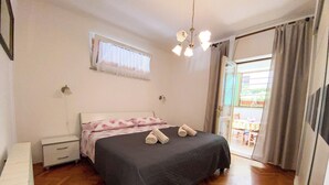Une chambre à coucher avec un lit, des tables de chevet, une fenêtre avec des rideaux et une vue sur l’extérieur.