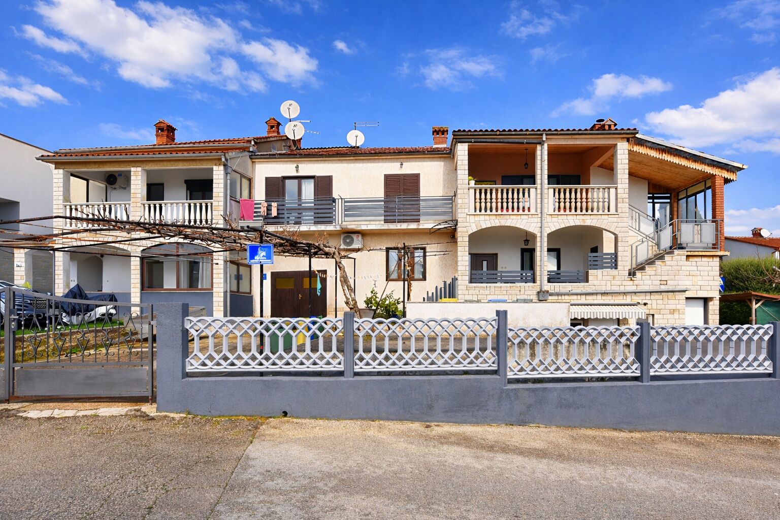 Una casa a due piani con un balcone, un garage e un cancello.