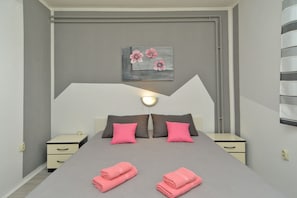 Relax in this serene bedroom with a large bed, two nightstands, and a wall-mounted light fixture.