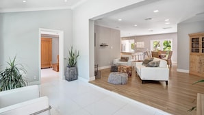 A spacious living area with a wooden floor, white sofas, and a kitchen in the background. - Modern Oasis in Tropical Serene Victoria Park/Private Pool/Near Beach Las Olas (Fort Lauderdale)