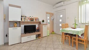 A compact living space with a TV, bookshelf, and dining area. - Apartment 624/1489 (Istria - Pula), 2500m from the beach (Pula)