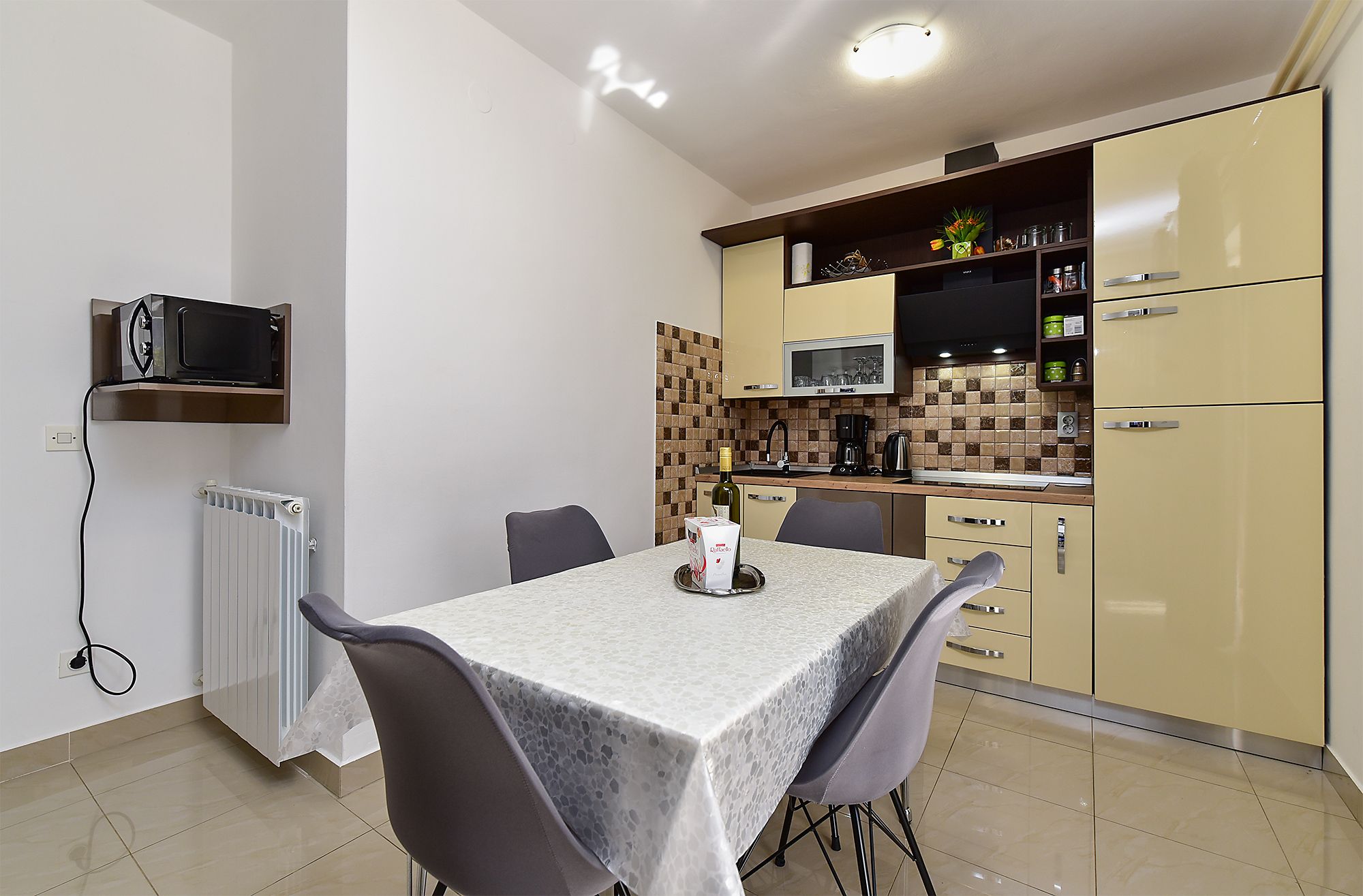 A compact kitchen with a dining area, including a table with chairs, a microwave, and a coffee maker.
