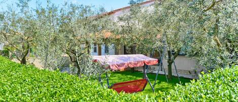 A garden with a swing set, a picnic table, and a red chair.