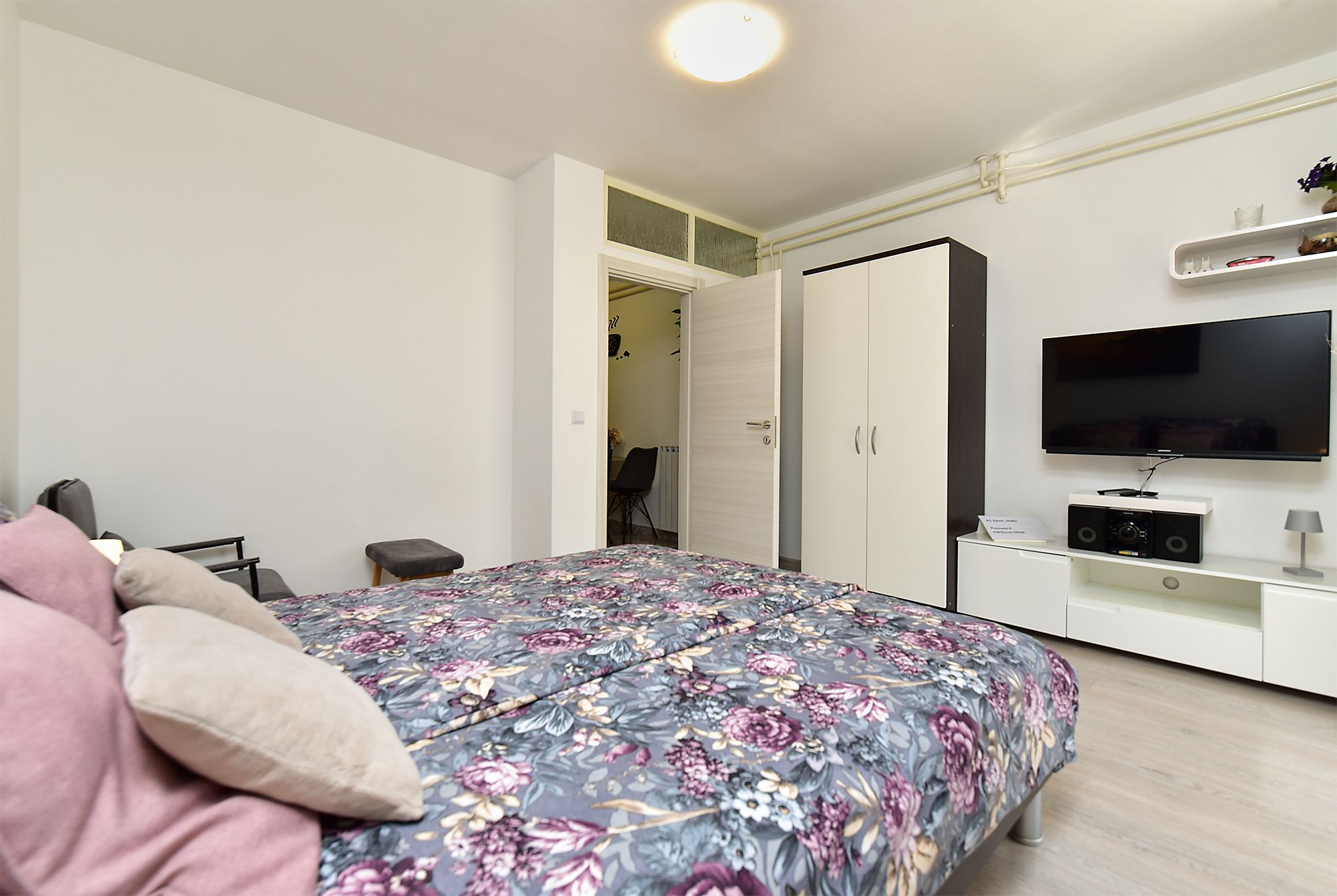 Ein Schlafzimmer mit einem Bett, einem Fernseher, einem Kleiderschrank und einem Schreibtisch.